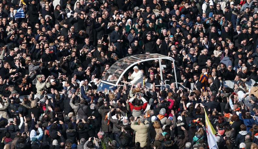 Pope Benedict XVI waves from his Popemobile as he rides through a packed Saint Peter's Square at the Vatican during his last general audience