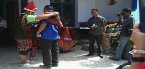 Pastor Yustinus Guru Kedi mengalungkan selempang di bahu Sekretaris Eksekutif Komsos KWI Pastor Kamilus Pantus saat tiba di Sumba