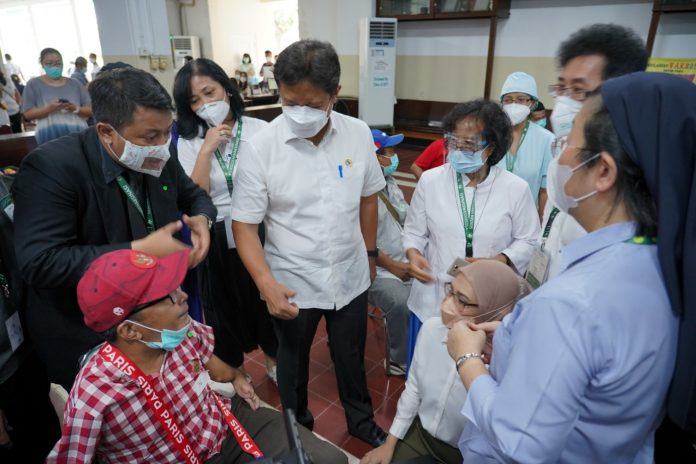 Menteri Kesehatan, Budi Gunadi Sadikin, bersama Staf Khusus Presiden Bidang Sosial, Angkie Yudistia, berbincang-bincang dengan salah seorang akseptor disabilitas, Vicente Mariano (38 tahun), di Sentra Vaksinasi Serviam, Kamis (25/3)