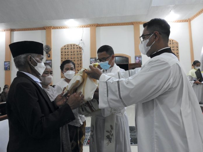 Romo Markus Ngatun Suparno Pr menerima jubah dan dibantu kedua orangtuanya dan saudara kandungnya memakai busana imamatnya. (Angel Li)