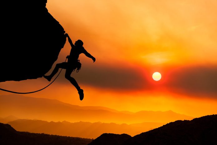 Climber gripping the edge of a cliff.